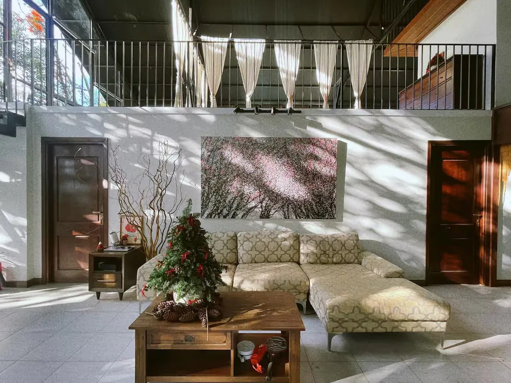Sunlit living area with a sofa, coffee table and mezzanine above.